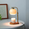A brass aromatherapy wax melting lamp with a frosted glass shade and a candle sits on a white table.