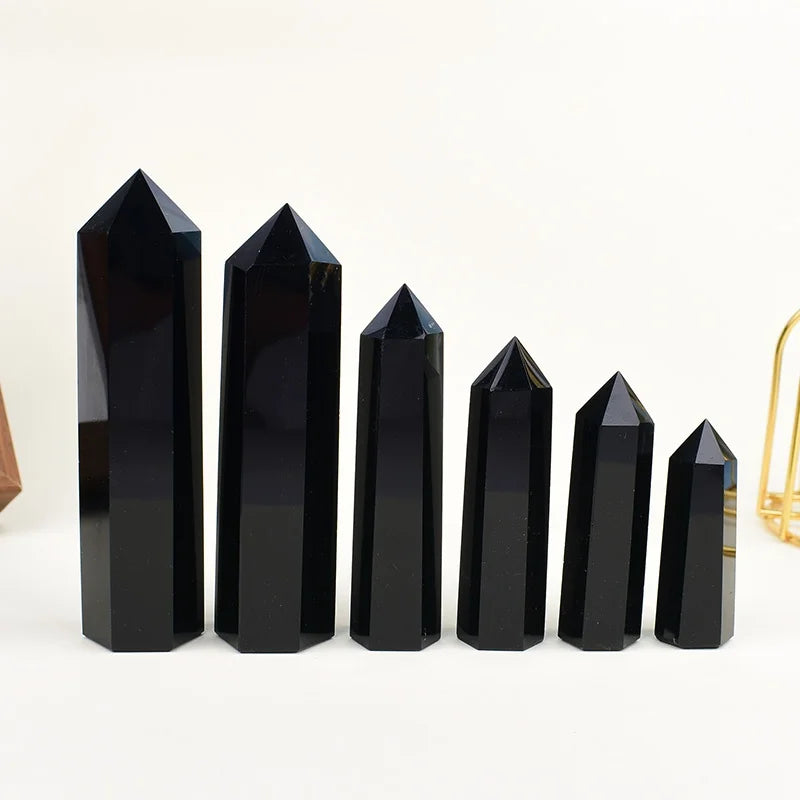 A row of black obsidian crystal obelisks or points standing upright on a white surface.