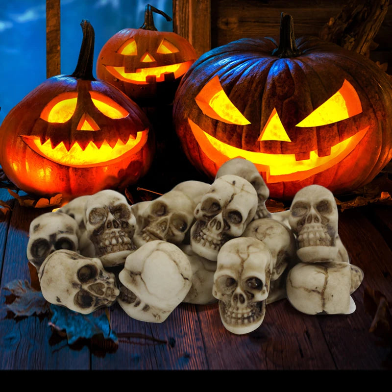 A set of 20 realistic resin mini skulls for garden decor displayed alongside carved pumpkins.