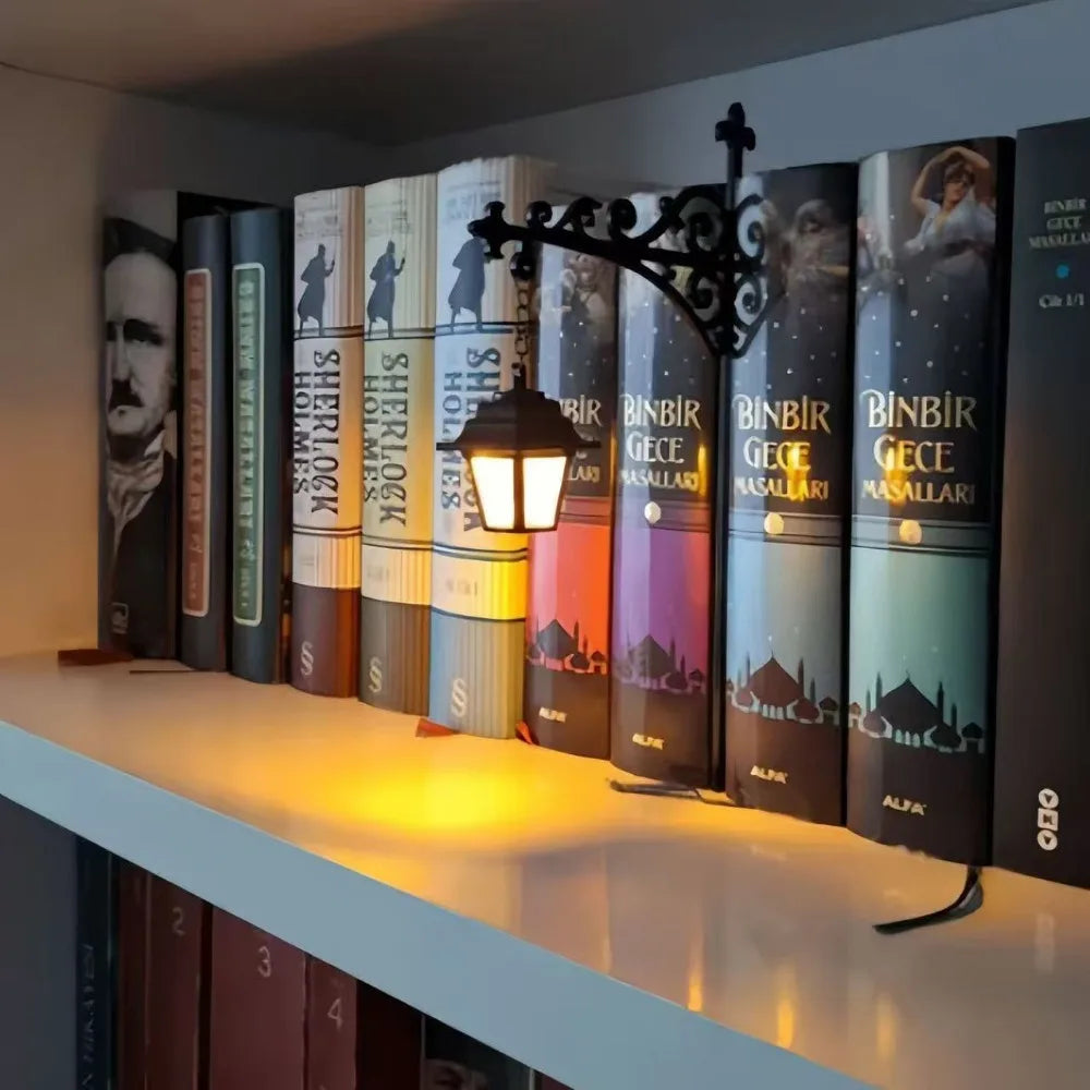 A row of vintage books is illuminated by a decorative lantern lamp on a white shelf.