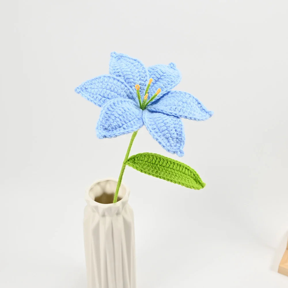 Hand-crocheted blue lily flower with a green leaf in a vase