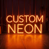 A glowing orange neon sign spelling out CUSTOM NEON on a wooden floor.