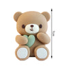 A cute brown teddy bear shaped cake topper with pink ball decorations and a measuring scale.