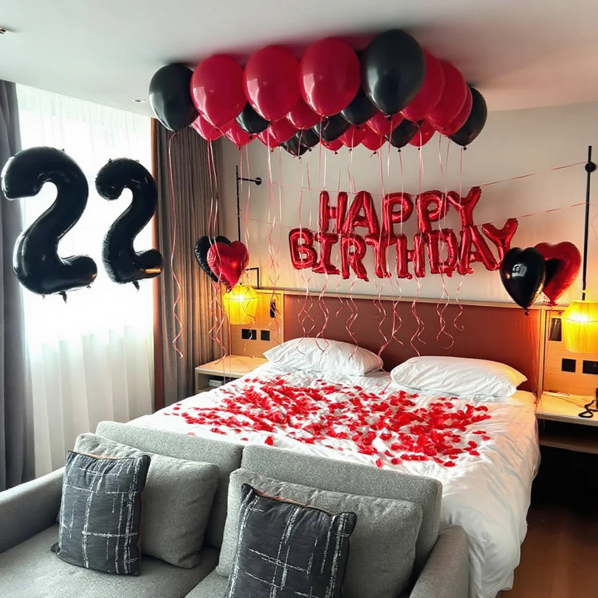 A bedroom decorated for a birthday with red and black balloons spelling out Happy Birthday 22