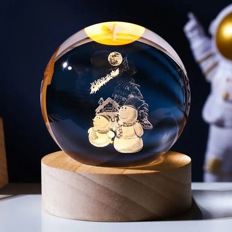 A dark blue crystal ball decoration featuring a snowy landscape and a golden sun, displayed on a wooden stand.