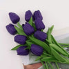 A bouquet of deep purple artificial tulips with green leaves.