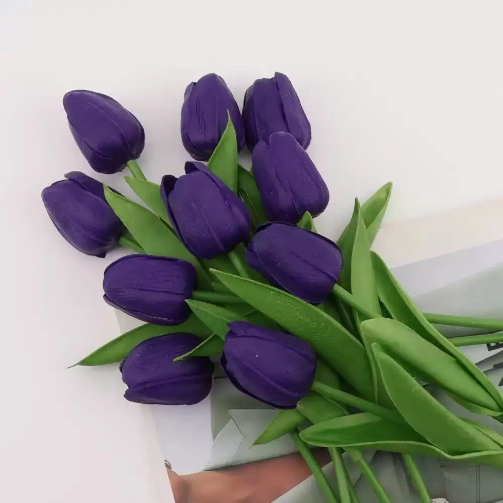 A bouquet of deep purple artificial tulips with green leaves.