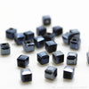 A collection of small, square-cut glass crystal beads in various shades of dark gray and black.