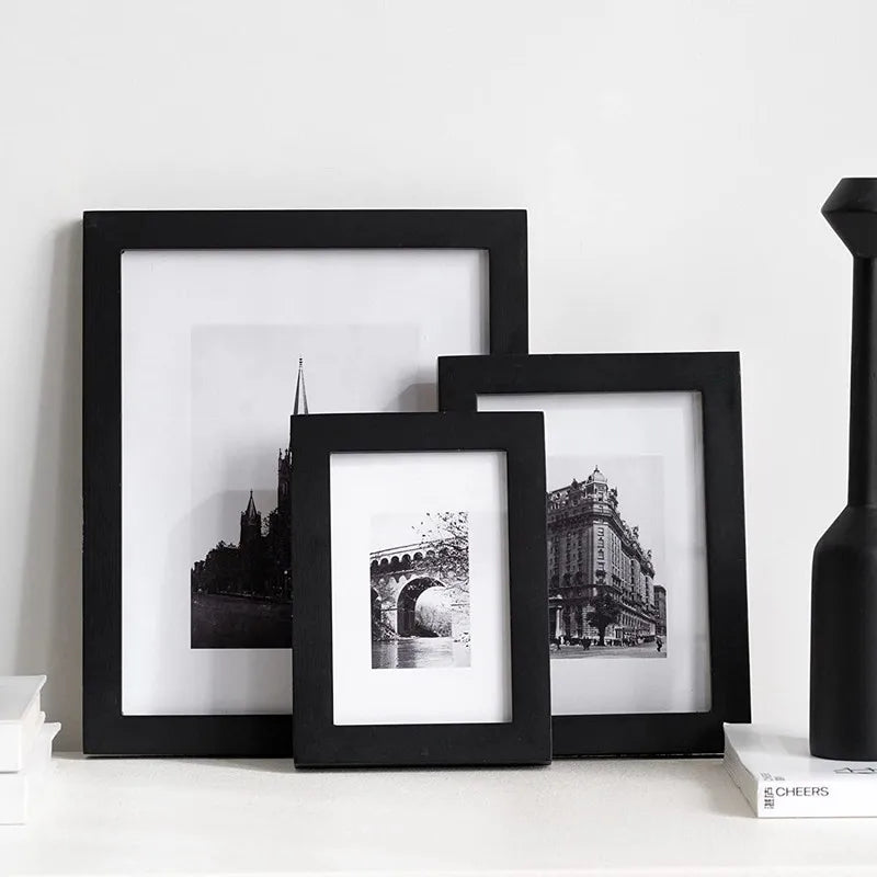 A set of three black picture frames displaying historical or architectural photographs on a white surface.