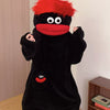A black monster onesie pajama suit with red accents is displayed on a light wooden floor.