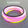 A set of ten luminous silicone bracelets in various colors including pink, yellow, and orange, displayed on a dark surface.