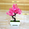 A vibrant pink artificial bonsai tree decoration planted in a white rectangular pot.