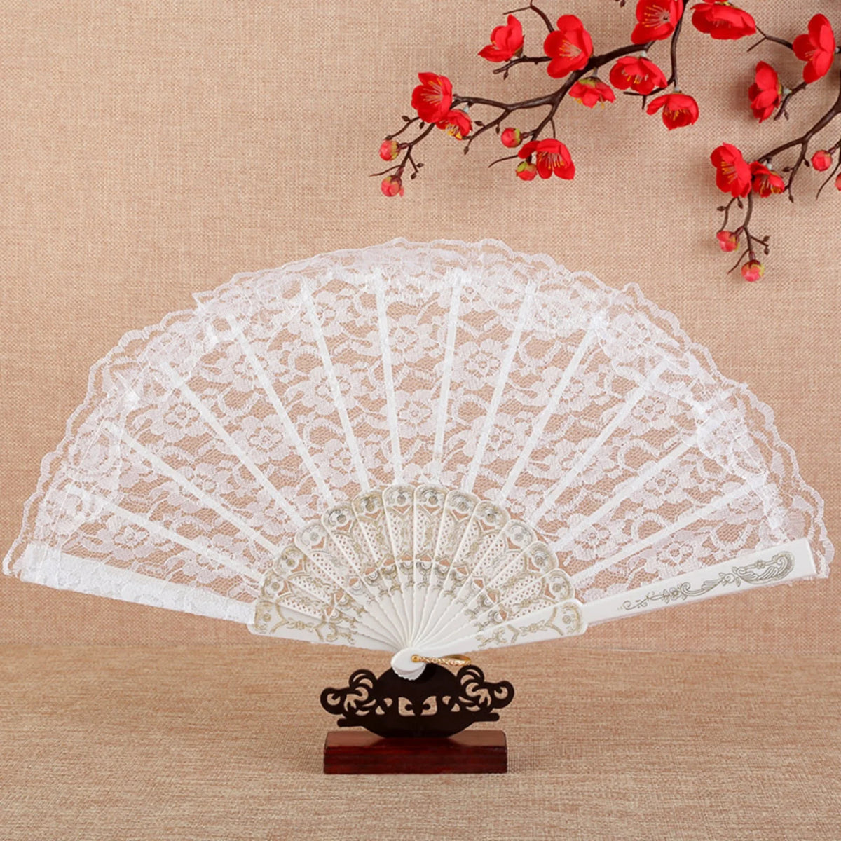 Abanico de mano plegable de encaje vintage blanco con base negra decorativa y ramas florales rojas.
