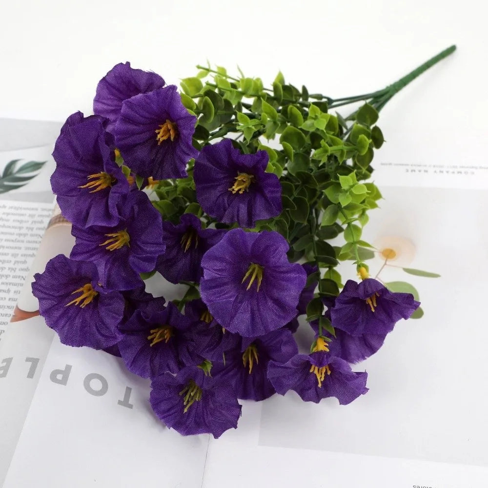 A bouquet of artificial purple pansy flowers with green eucalyptus stems