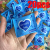 A hand holds a blue mystery bag product with a heart design, surrounded by other similar bags.