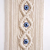 Macrame wall hanging featuring a woven design with multiple blue and white evil eye pendants.