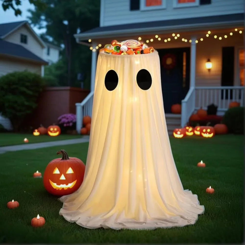 An adjustable glowing ghost Halloween treat bucket draped in sheer white fabric on a green lawn.