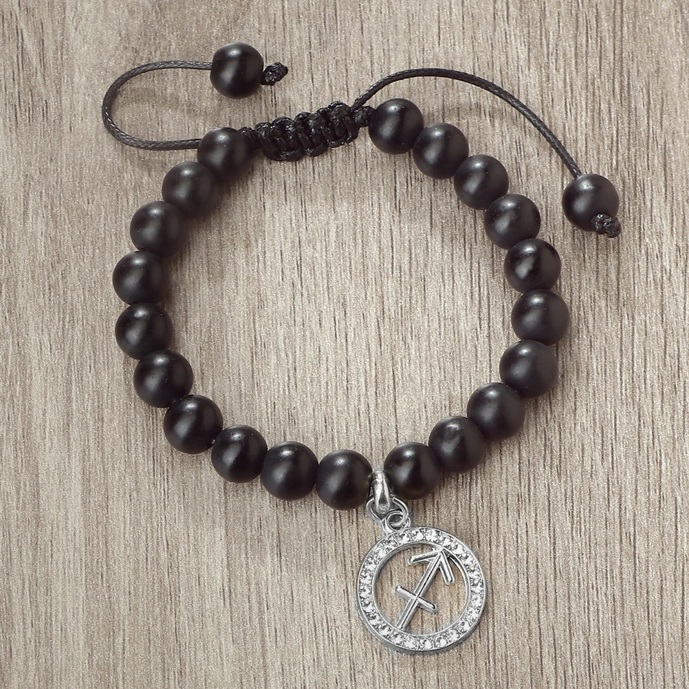 A handmade beaded bracelet with natural black stones and a silver zodiac charm