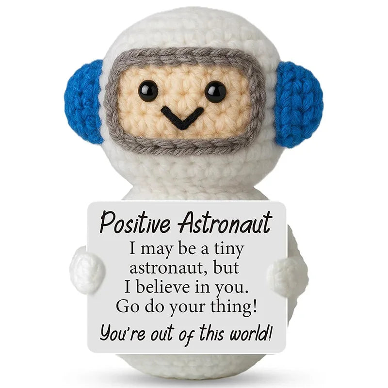 A handcrafted crochet astronaut doll wearing a helmet with a positive message card that says I believe in you go do your thin
