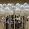 A white pearl latex balloon garland decoration hanging in front of a window.