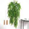 A lush green artificial plant vine wall hanging cascading down a white wall.