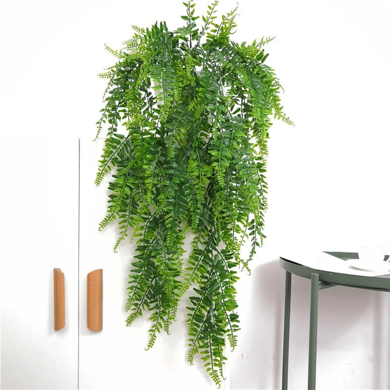 A lush green artificial plant vine wall hanging cascading down a white wall.