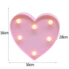 A pink heart-shaped LED light featuring multiple warm white alphabet letters.