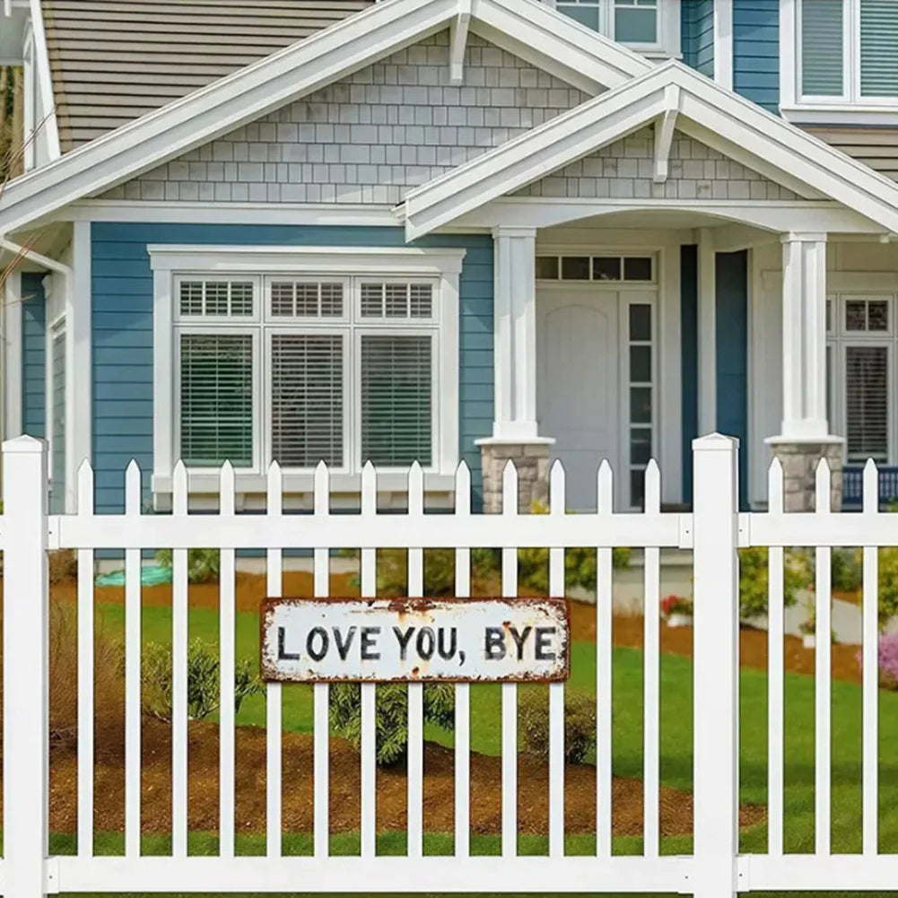 White picket fence in front of a blue and gray house with a white porch and window.