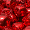 A close-up view of a pile of glossy red round foil balloons for celebrations.
