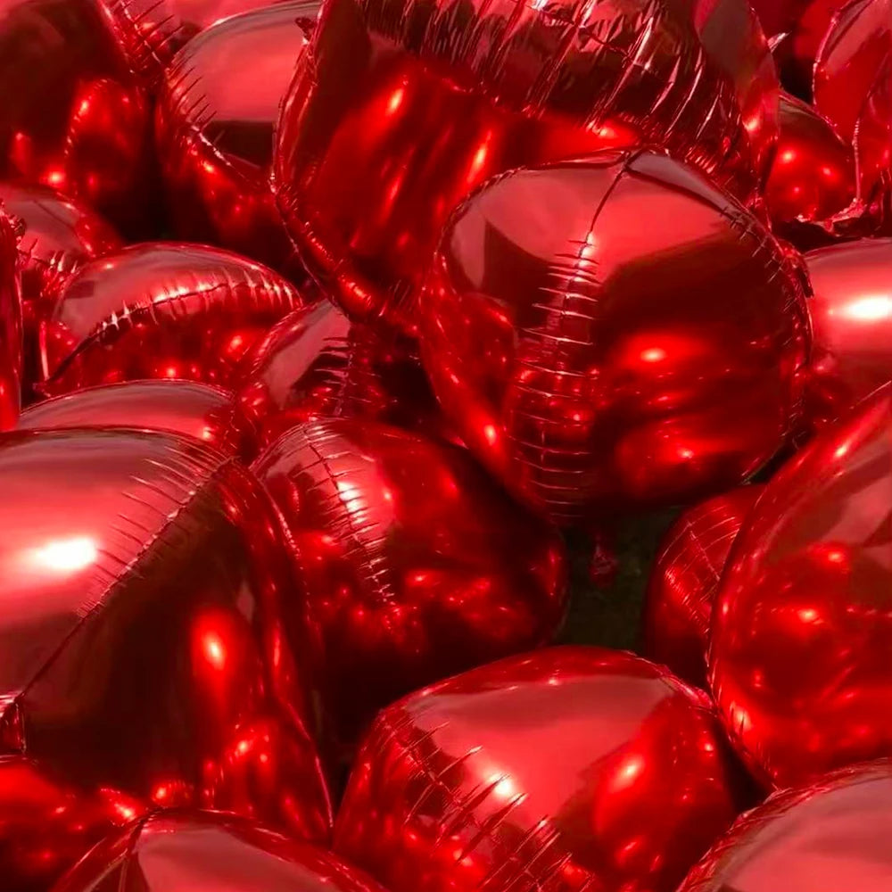 A close-up view of a pile of glossy red round foil balloons for celebrations.