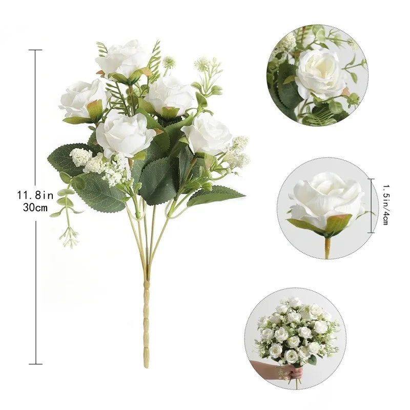 A bouquet of white silk touch artificial roses with green leaves and small white filler flowers.