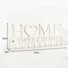 A white metal key holder with the words HOME SWEET HOME cut into the design, featuring wall-mounted hooks.