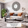A modern minimalist metal wall clock with radiating spikes hangs above a light gray sofa in a contemporary living room.