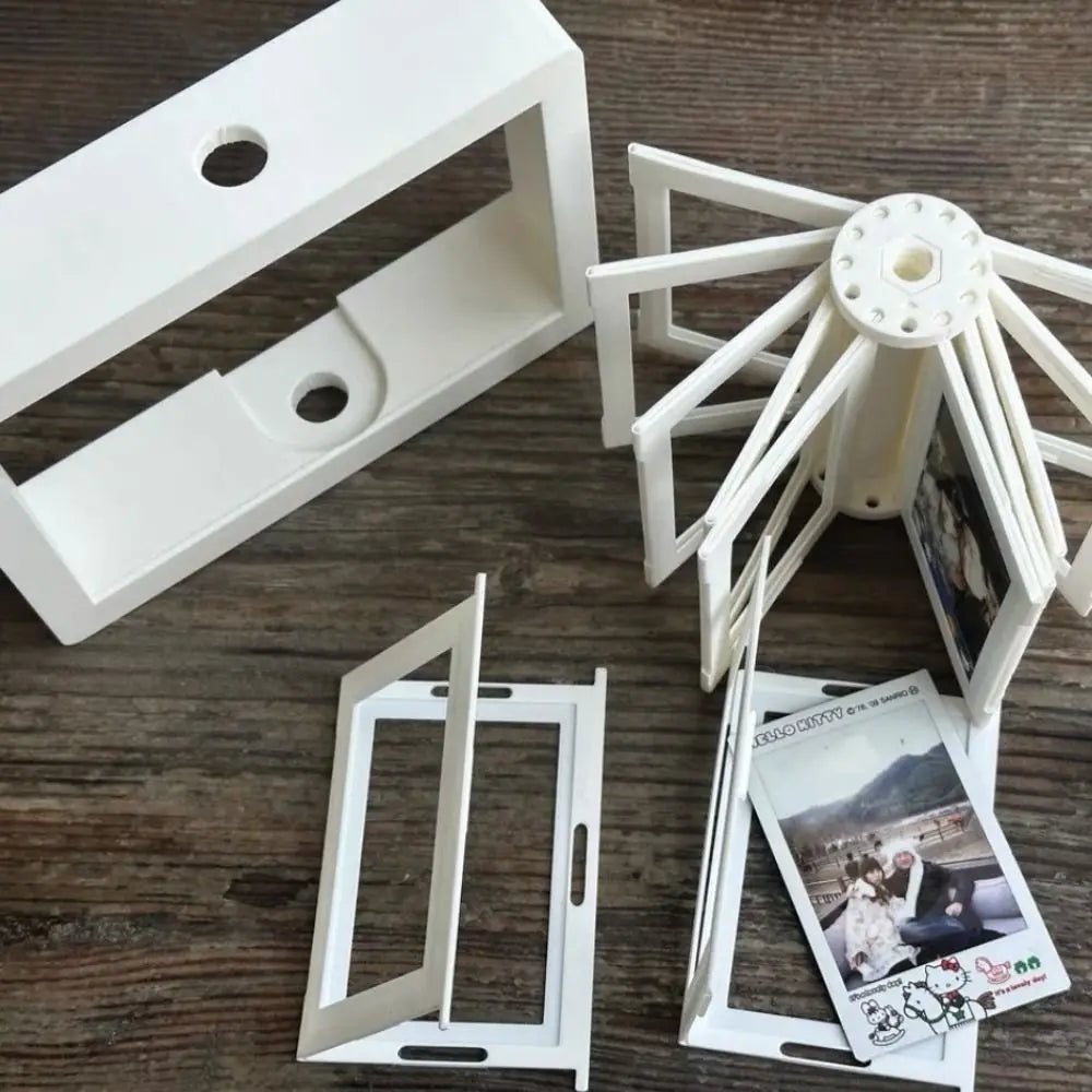 White 3D rotating photo holder with twelve clear display pockets shown from above.