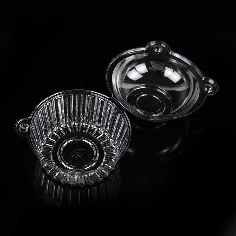 A clear plastic cupcake box with a lid is shown against a black background.