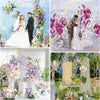 Three gold metal arched wedding backdrop stands displaying floral arrangements for a wedding ceremony.