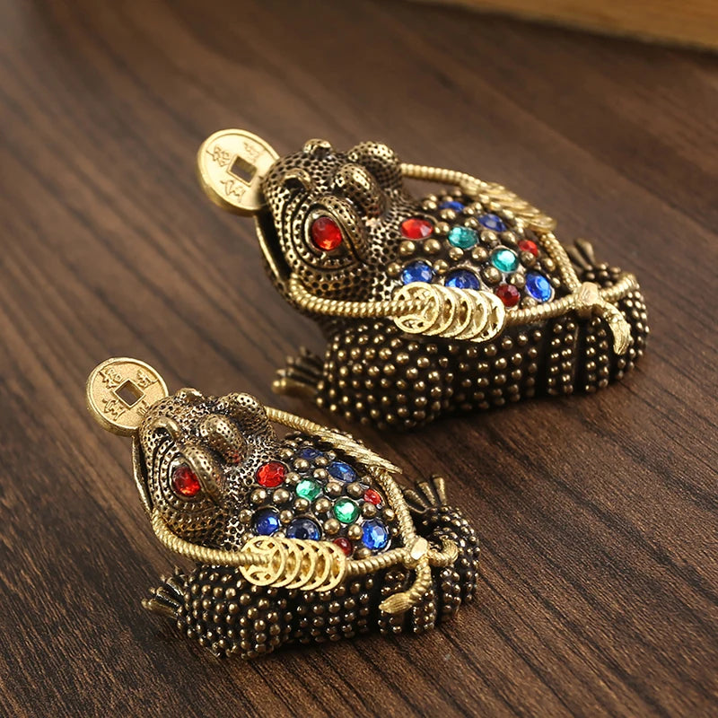 Figurita de toad chino dorada detallada, adornada con joyas y una moneda.