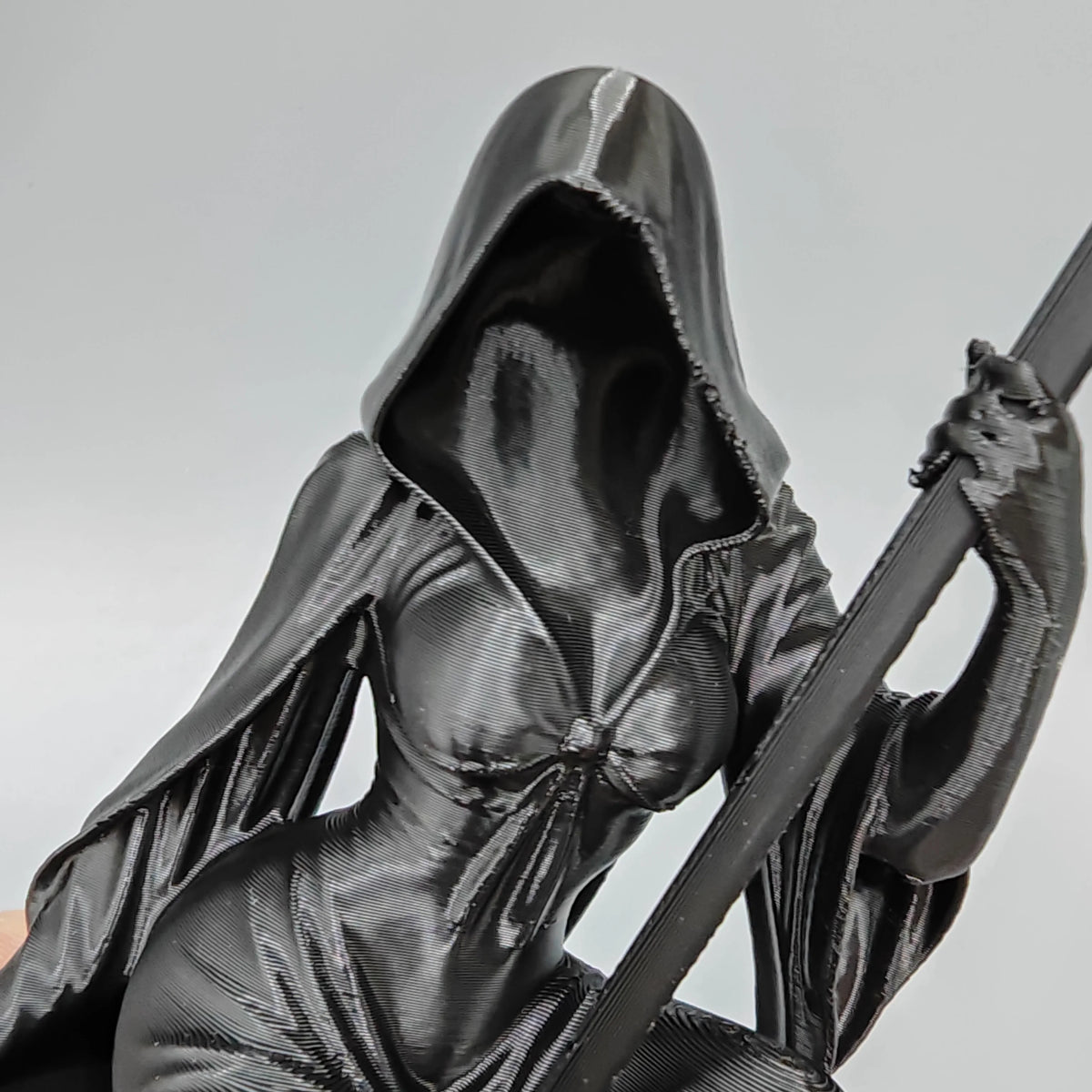 A black gothic female grim reaper figurine with a scythe, shown in a close-up view.