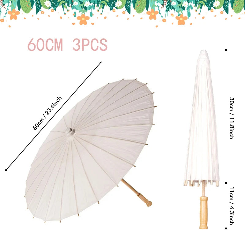 A white oil paper umbrella is shown open and a closed version standing upright, with decorative greenery above.