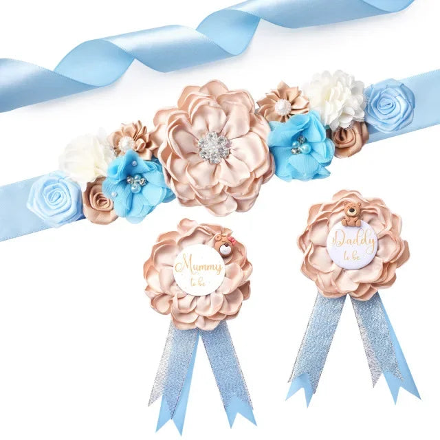 A set of floral maternity sash and corsage pins featuring pink, blue, and white roses and greenery.