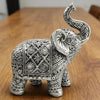 Silver resin elephant sculpture with intricate detailing, displayed on a wooden surface.