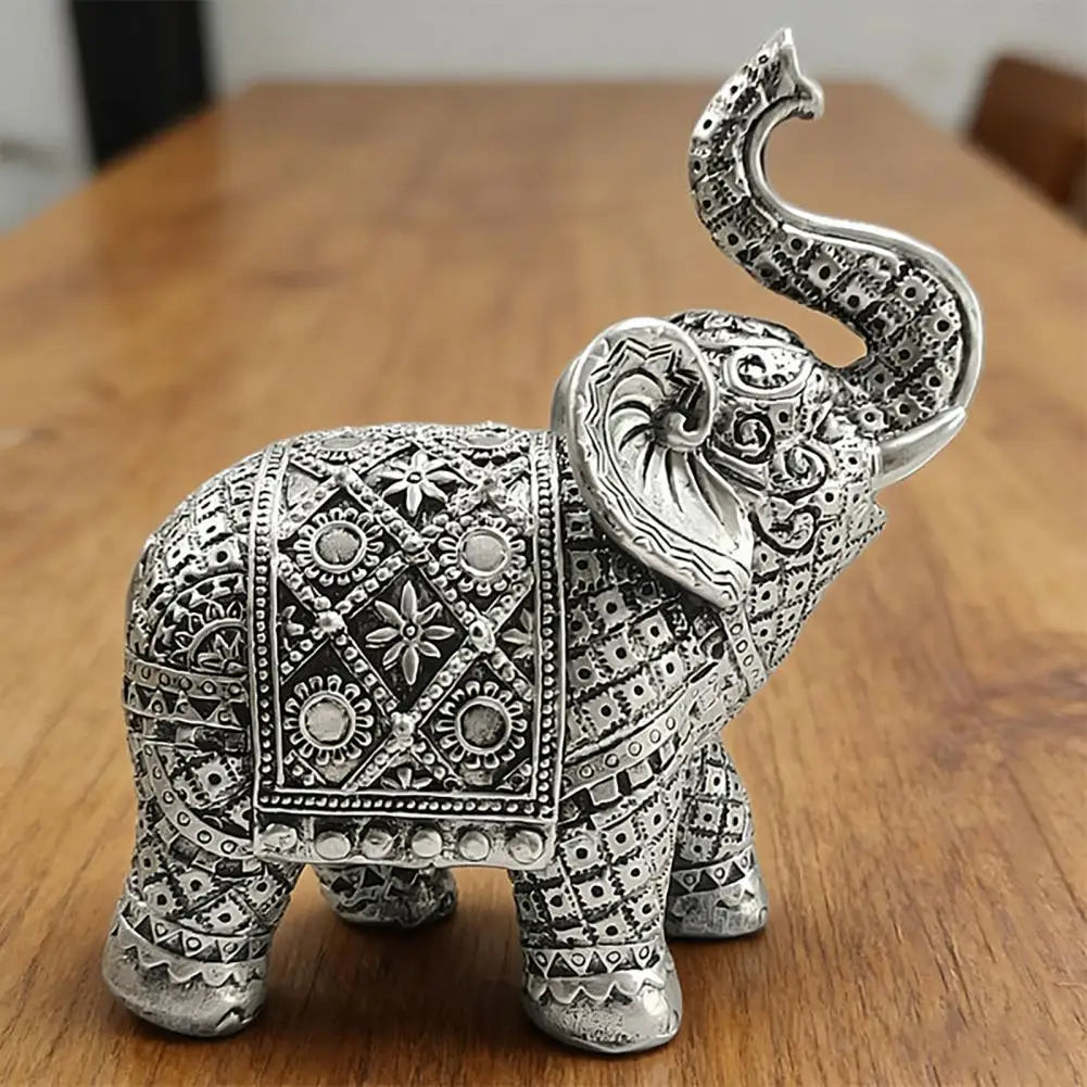 Silver resin elephant sculpture with intricate detailing, displayed on a wooden surface.