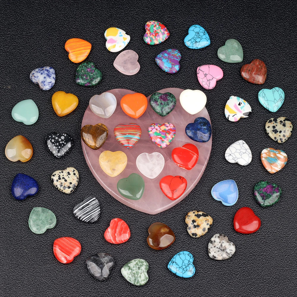 A collection of heart-shaped amethyst crystal stones in various colors and shades scattered on a dark surface.