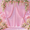 A pink fabric backdrop with draped curtains and floral garlands, set up for an event.