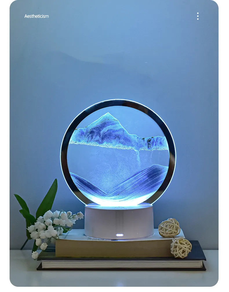 A 3D Quicksand LED table lamp with a blue color-changing light illuminating a mountain landscape.