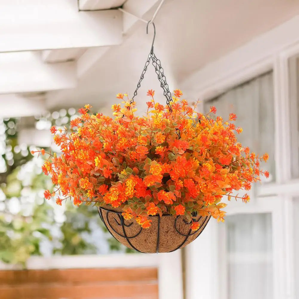 A realistic artificial flower hanging basket filled with bright orange and yellow blossoms, suspended from a ceiling hook.