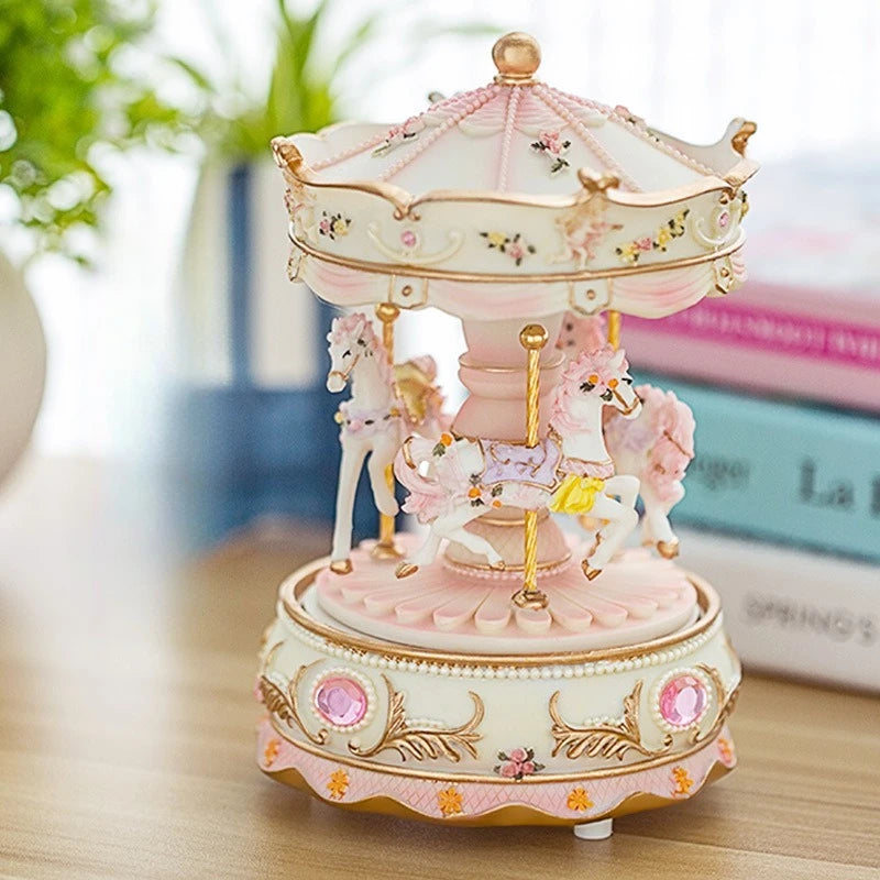 A delicate pink and cream resin carousel music box with horses and a domed lid.