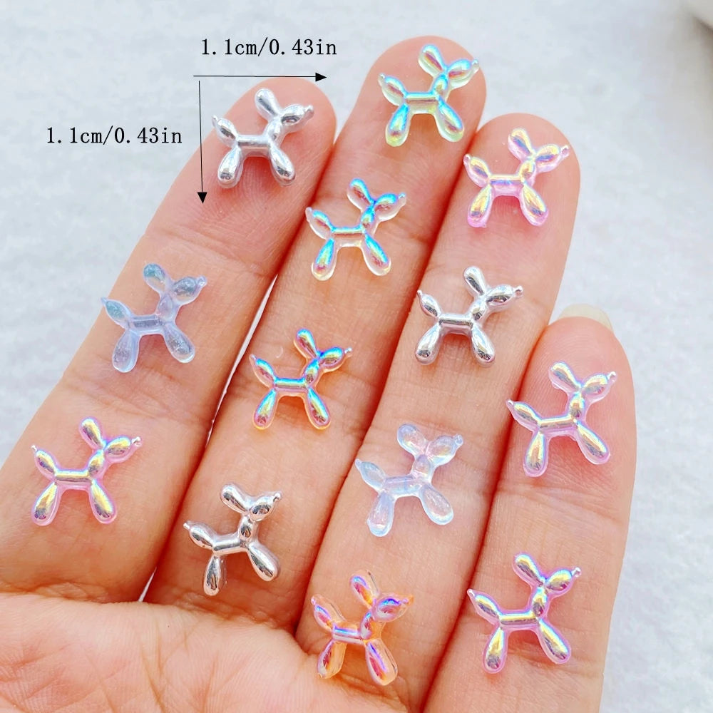 A hand displays various cute balloon puppy nail art charms on the fingernails.