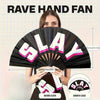 A woman holds open a black hand fan with the word SLAY printed on it, showing its size and smooth close feature.