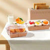 A display of various pastries and bread items in minimalist kraft boxes on a white table.